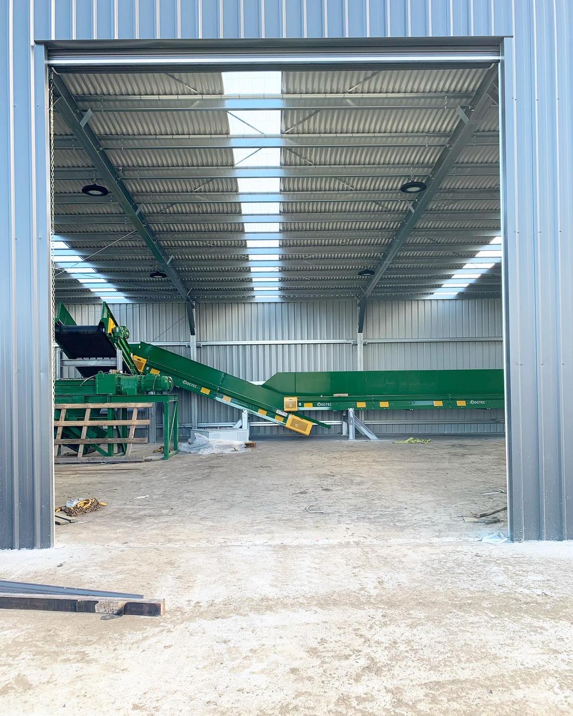 Photo of large shed looking through the door at new machinery with conveyor belts and chutes.